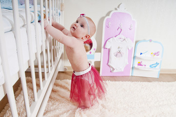 Little baby girl ( 7 mounth old ) standing at children's room ne