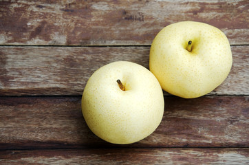 Asian pears on a wooden floor in the background.