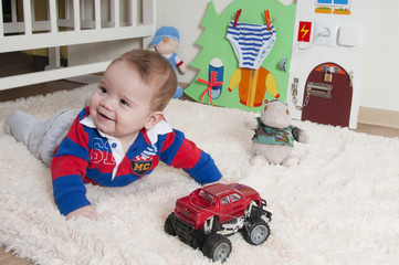 Baby boy is playing on the carpet at home or in the kindergarten