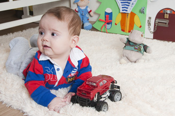 Baby boy is playing on the carpet at home or in the kindergarten