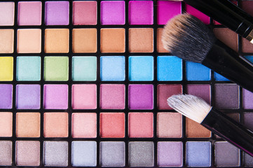 make-up brushes on colorful eye shadows palette