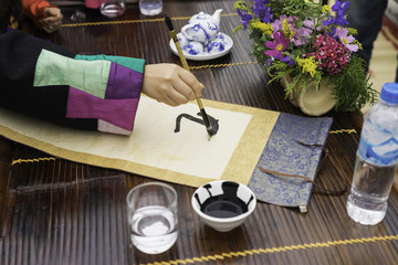 Naklejka na ściany i meble Calligrapher painting words on paper. Calligraphy is a traditional culture in Eastern lunar new year. Focus on the text