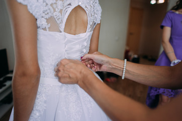 Obraz na płótnie Canvas bridesmaid tying bow on wedding dress