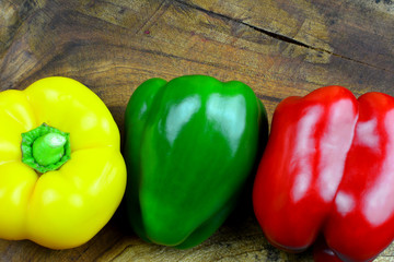 Hintergrund für vegetarische und vegane Speisekarte - Roter, grüner und gelber Paprika am Holzbrett mit Textfreiraum