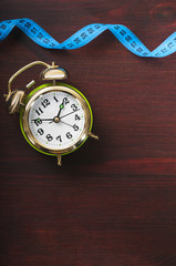 measuring tape and alarm clock on the wooden background