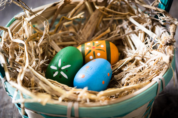 Colored easter eggs in a basket on wooden table
