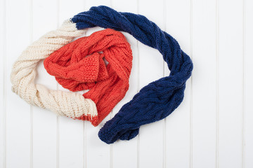 Colorful woolly hat and scarf on white wooden background.