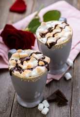 S'mores drink. Two mugs of hot chocolate with marshmallows on a wooden table. Cocoa. Rose petals. Valentine.