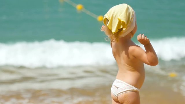 Little girl standing against ocean waves
