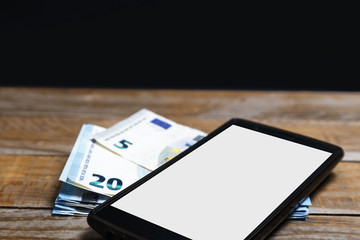 Amounts of euro banknotes and a mobile phone on an old wood
