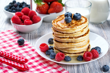 Stack of pancakes with fresh blueberry, raspberry and honey, milk and fresh berries, healthy breakfast concept