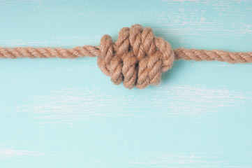 Marine rope with a knot on a wooden background turquoise