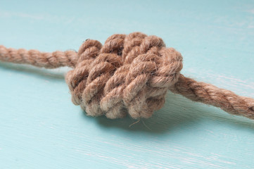 Marine rope with a knot on a wooden background turquoise