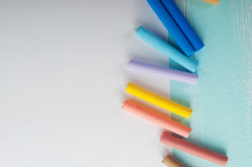 Blank sheet of paper and pastels on turquoise wooden surface