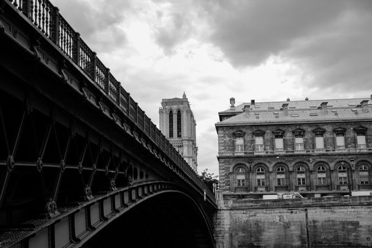 Fototapeta Bridge over the Seine river, tower of the Notre Dame cathedral in Paris, black and white 