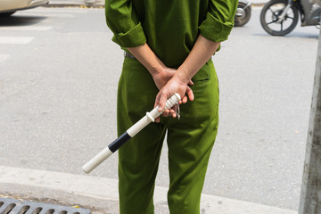 Closeup back view of Vietnamese traffic police with green uniform and club