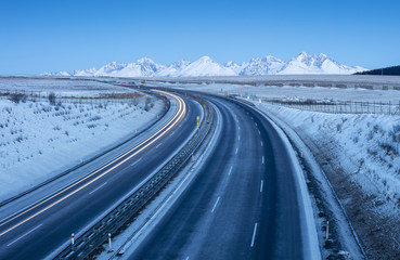 free highway in morning time and snowed mountains on horizon