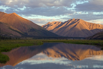 Mountains in sunset light and reflections in the lake. Ridge Cherskogo. Yakutia. Russia.