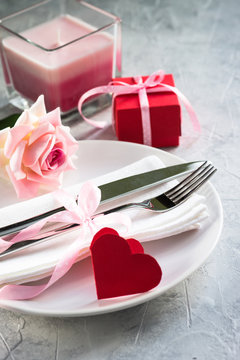 Valentines day table setting. Plate silverware heart decorations flower.