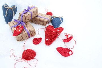 Вязанные крючком сердца и подарки на белом снегу