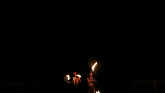 two boys artist performing fire show at night. fire breather spitting flame in slow motion