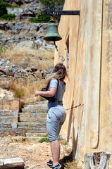 The girl rings the old bell in Greece.