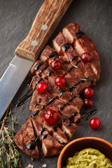 Grilled sliced beef steak with cranberry, balsamic vinegar, thyme and spices on a slate plate. The pesto sauce. Top view
