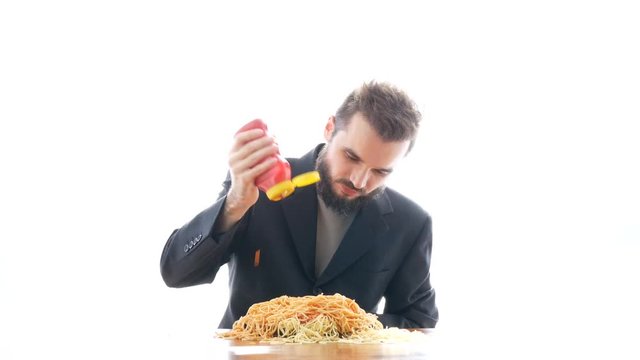Nasty mad businessman eating pasta with ketchup on the table. Overeating and crazy greedy consumerism concept, studio isolated on white background.