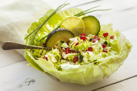 Bowl of green salad of cucumber, escarole and avocado,with pomeg