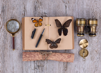 Fototapeta premium notebook, butterfly collection, magnifier and vintage binoculars on an old rustic table