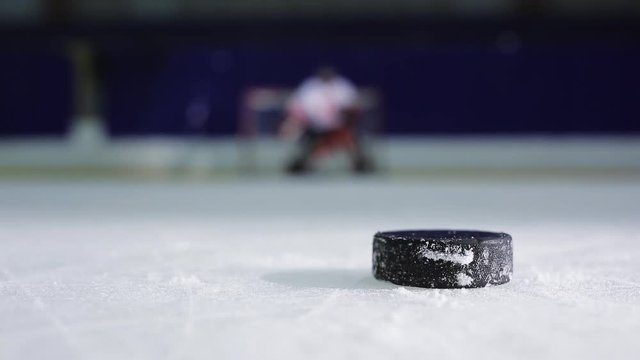 Ice hockey player holding a demonstration a free throw into the opponent's gate. Clouse up Ice hockey puck and drove to her scores in the opponent's net.