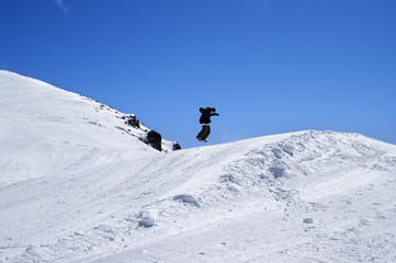 Fototapeta na wymiar Snowboarder jumping in snow park at ski resort on sun winter day