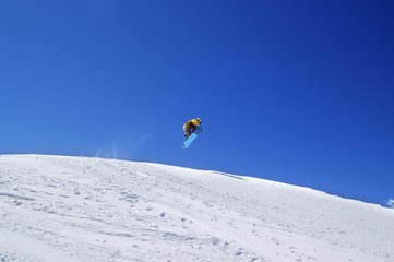 Snowboarder jump in terrain park at ski resort on sun day