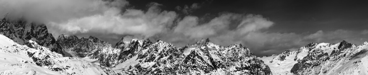 Black and white large panoramic view on snow mountains in haze a