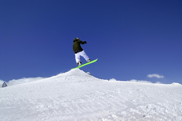 Naklejka na ściany i meble Snowboarder jump in snow park at ski resort on sun winter day