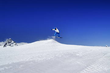 Naklejka na ściany i meble Snowboarder jump in snow park at ski resort on sunny winter day