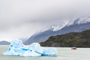 Floating iceberg and a small boat in Grey glacier lake, Torres del Paine National Park, Patagonia, Chile