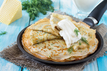 Not sweet pancakes with cheese and fresh dill in a cast iron ski