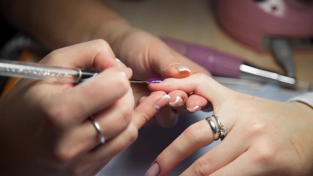 Manicurist paints woman's nails by brush, woman comes to the manicure salon, nail care, business in beauty