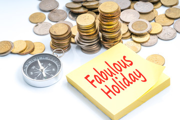 Coins and compass with text sticky note. Travel and holiday concept