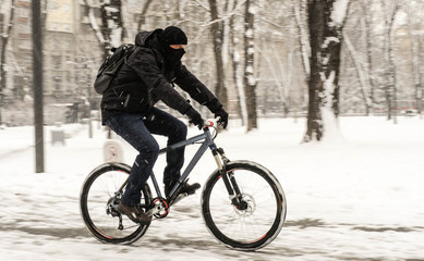 A man rides a bicycle in snowy weather