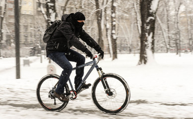 Fototapeta premium A man rides a bicycle in snowy weather