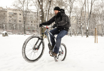 Fototapeta na wymiar A man rides a bicycle in snowy weather