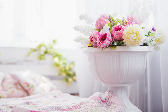 Pink and white flowers in a vase near the bed