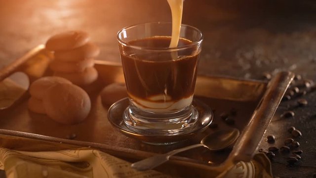 Coffee in a transparent glass. with pouring condensed milk on metal tray