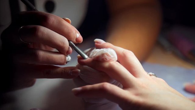 Manicurist makes edging manicure, woman comes to the manicure salon, nail care, business in beauty