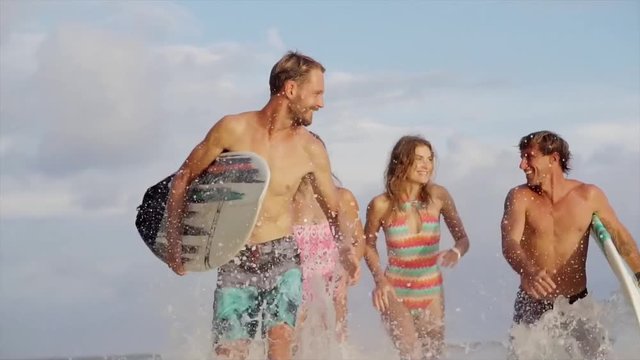 Group of happy friends with surfboard running on sandy beach in Bali