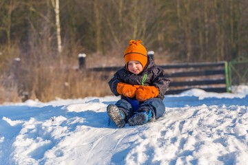 Fototapeta na wymiar Happy little caucasian boy downhill on plastic slider or sledge