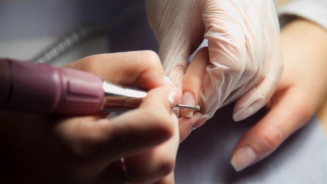 Manicurist makes hardware manicure, woman comes to the manicure salon, nail care, business in beauty