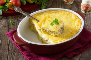 Casserole with potatoes, meat and cheese on a wooden table. Spac